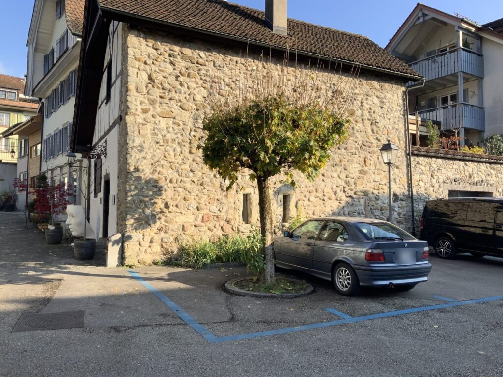 Parkplätze in der Blauen Zone neben einem alten Steinhaus
